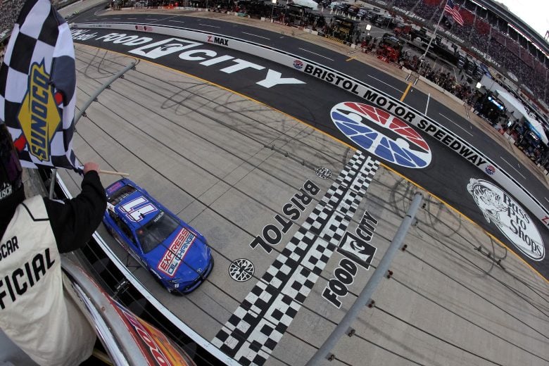 Jonathan Bachman | Getty Images - Denny Hamlin, driver of the No. 11 Express Oil Change Toyota, takes the checkered flag to win the NASCAR Cup Series Food City 500 at Bristol Motor Speedway.